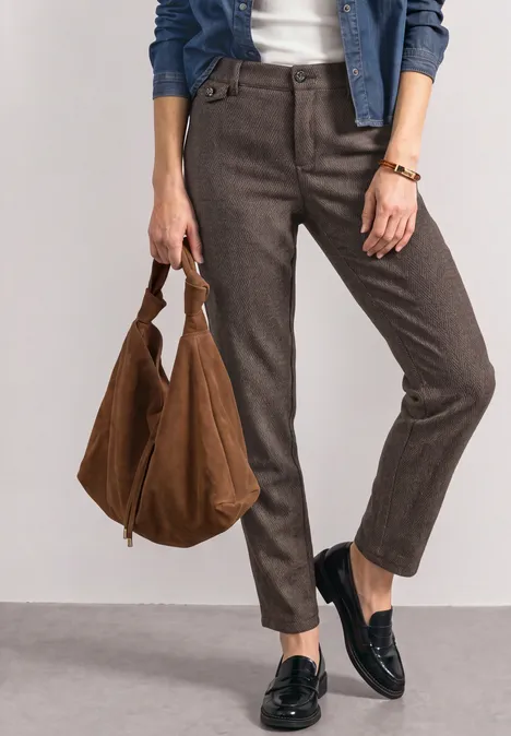 Mid Waist Chino im Casual Fit black coffee Frau in braunen Hosen, schwarzen Loafers und mit großer brauner Tasche.