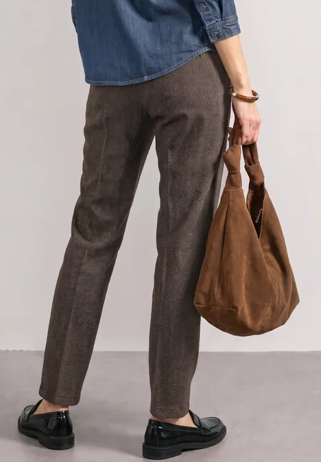 Mid Waist Chino im Casual Fit black coffee Frau trägt dunkle Hose, schwarze Loafers und eine braune Velourstasche, gesehen von hinten
