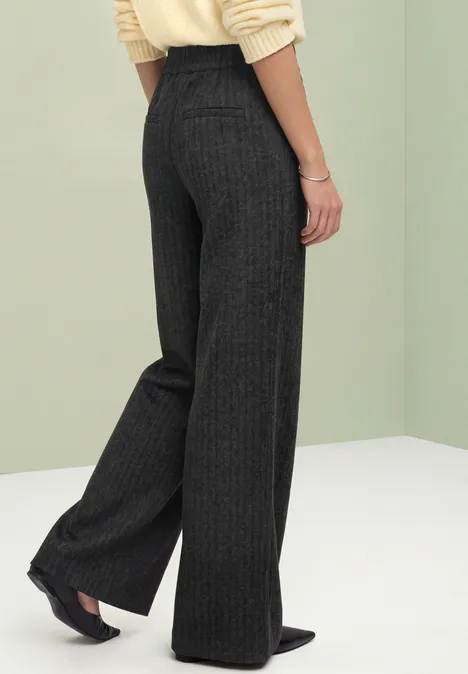 Stright Leg Hose mit Fishbone-Muster Black Von hinten sichtbare Person in dunkelgrauer Nadelstreifen-Hose mit weitem Bein und schwarzen Spitzschuhen.