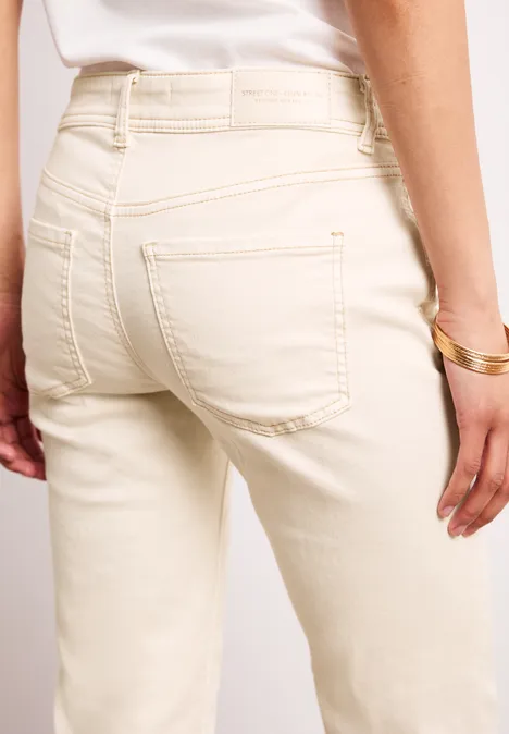 Rückansicht einer Person in cremefarbenen Jeans mit goldenem Armband.