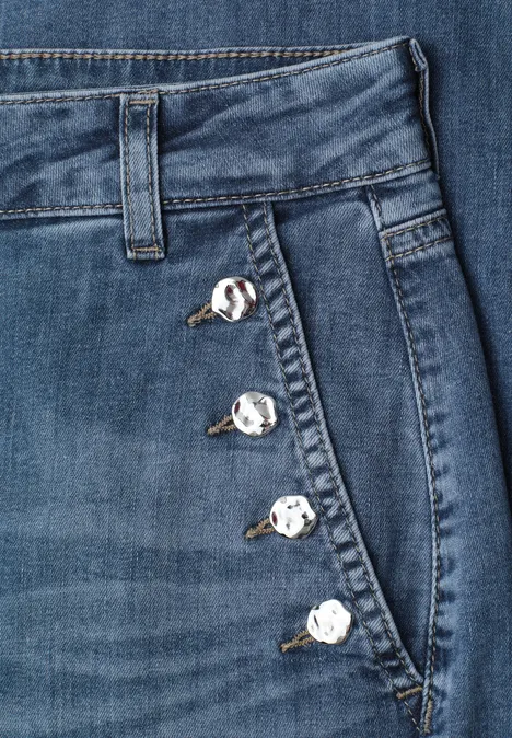 Blauwe jeans met zijzak en vier zilverkleurige knopen langs de naden.