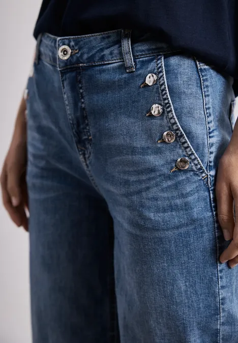 Blauwe jeans met zijwaartse knoopsluiting en zilverkleurige knopen, nonchalant model.