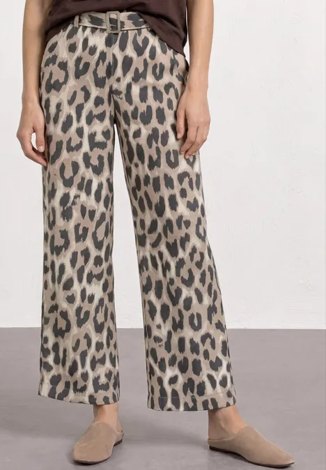 Weite Damenhose mit beigem und schwarzem Leopardenmuster, hohe Taille, kombiniert mit flachen Slippern.