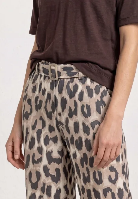 Eine Person trägt ein braunes T-Shirt und eine Leopardenmuster-Hose mit Gürtel.