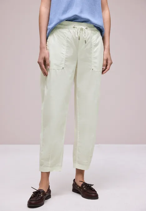 Studioaufnahme: Helle, locker sitzende Bundfaltenhose mit Kordelzug und braunen Loafers.