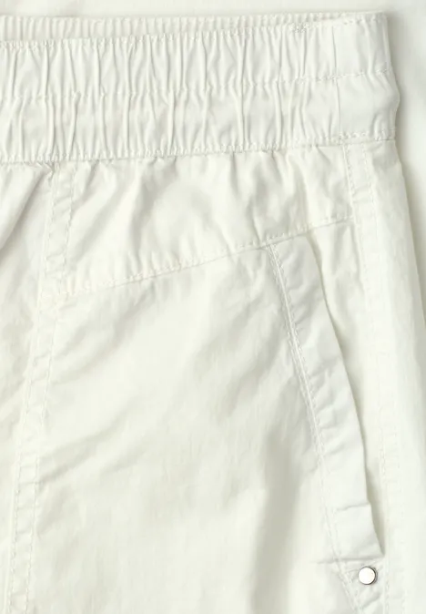 Nahaufnahme einer weißen Hose mit elastischem Bund und seitlicher Tasche mit Druckknopf.