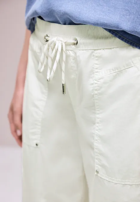 Helle, lockere Hose mit Tunnelzug und aufgesetzten Taschen, kombiniert mit einem blauen Shirt.