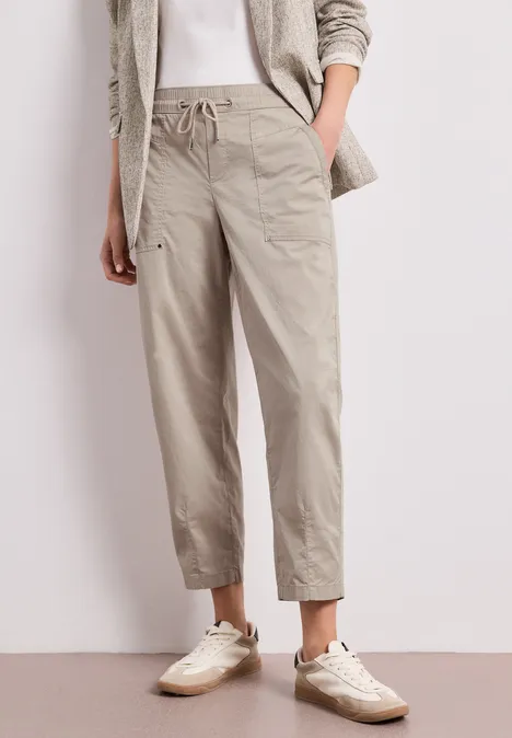 Locker-elegantes Outfit: weiße Sneakers, beige Kordelhose, weißes Top und leichter Blazer.