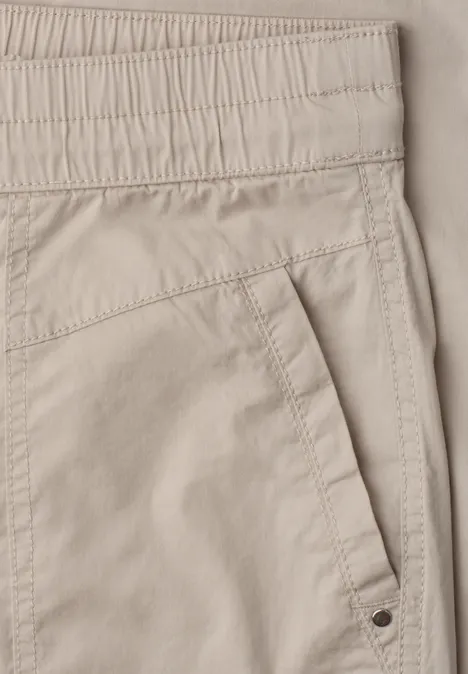 Beige Hose mit elastischem Bund und schräger Seitentasche.