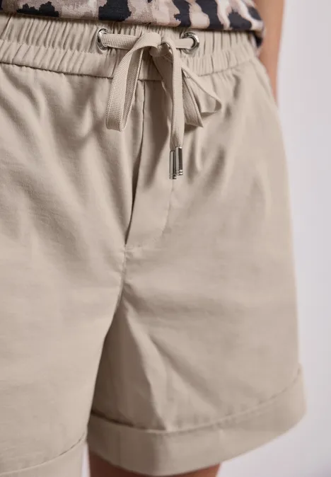 Beige korte broek met trekkoord en omgeslagen zoom, gecombineerd met een luipaardprint top.