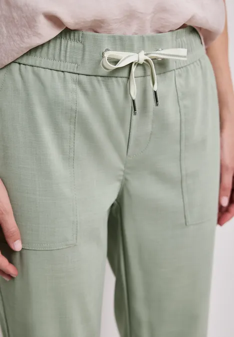 Helle, lockere grüne Hose mit elastischem Bund, Kordelzug und aufgesetzten Taschen.