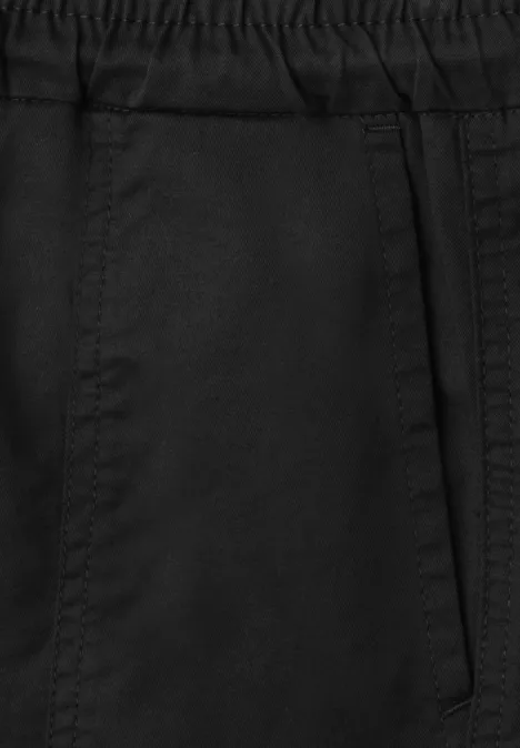 Nahaufnahme einer schwarzen Hose mit elastischem Bund und seitlicher Tasche.