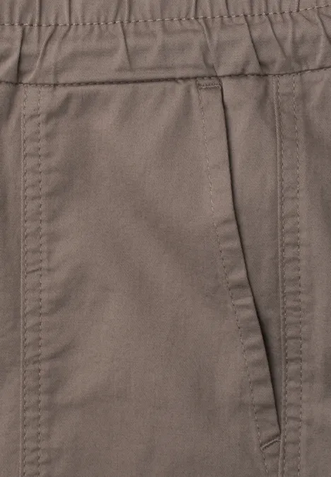 Close-up van een bruine broek met zijzak en zichtbare naden.