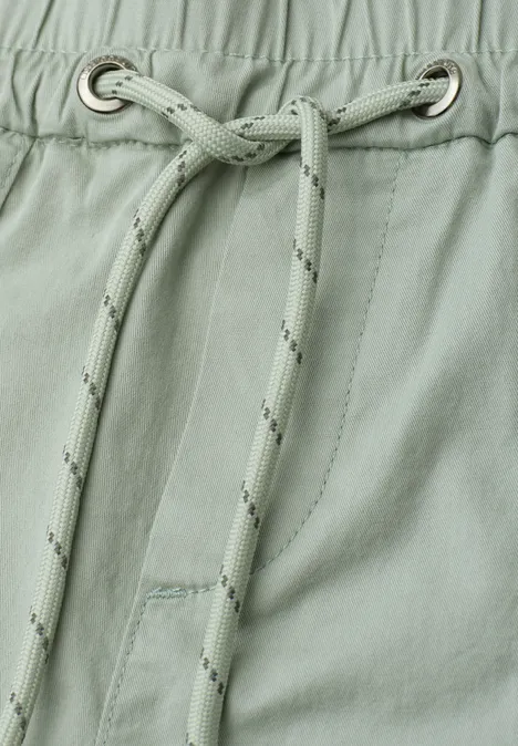 Nahaufnahme eines hellgrünen Kleidungsstücks mit Kordelzug und Metallösen