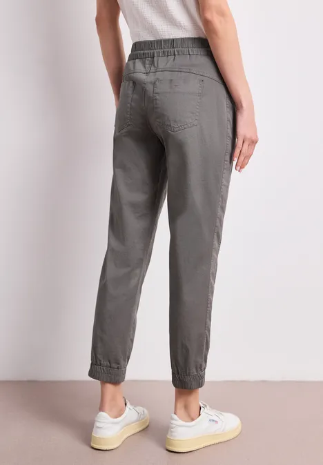 Modische graue Jogginghose mit elastischem Bund und Bündchen, leger geschnitten, kombiniert mit Sneakers.