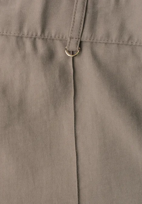 Close-up van kaki gekleurde stof met verticale naad en gouden D-ring.