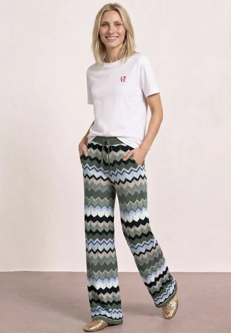 Frau mit weißem T-Shirt und weit geschnittener Hose mit wellenförmigem Muster