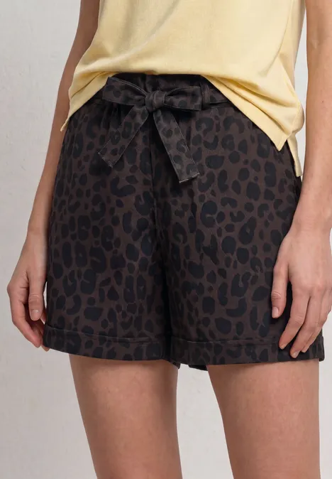 Dunkelbraune Shorts mit Leopardenmuster und Schleife in der Taille, kombiniert mit gelbem Oberteil.