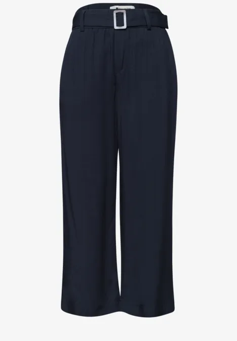 Dunkelblaue, weite Hose mit hohem Bund, eckiger Gürtelschnalle und eleganten Bügelfalten.
