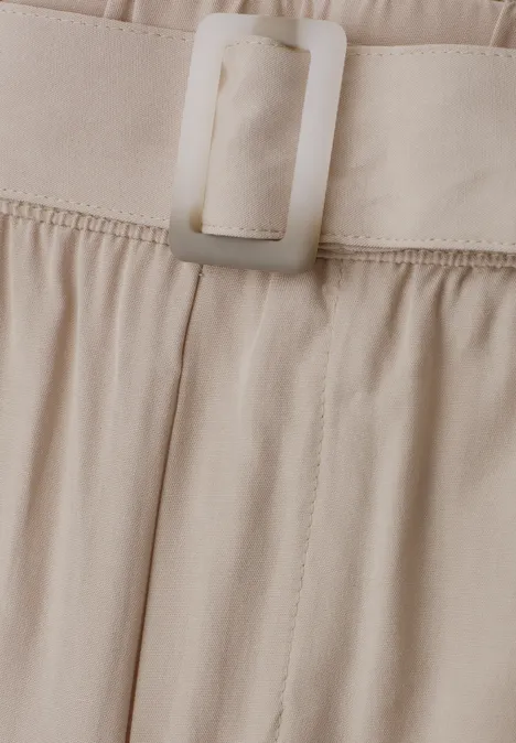Nahaufnahme eines beigen Stoffbunds mit rechteckiger Schnalle an einer Hose