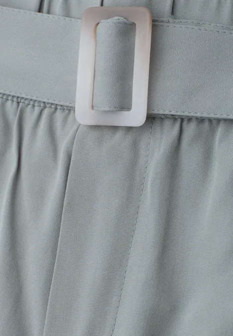 Close-up van een grijs kledingstuk met tailleriem en rechthoekige metalen gesp.