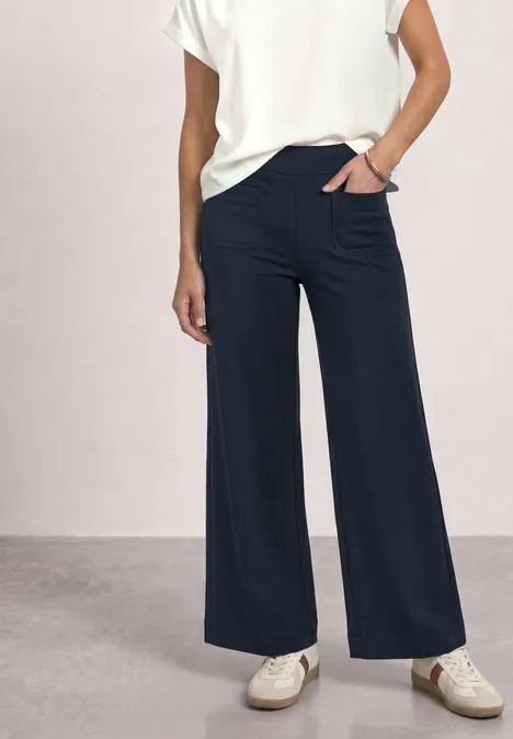 High Waist Straight Leg Hose im Casual Fit shadowed navy Person trägt weiße Bluse, weite dunkelblaue Hose und weiße Sneaker vor neutralem Hintergrund.