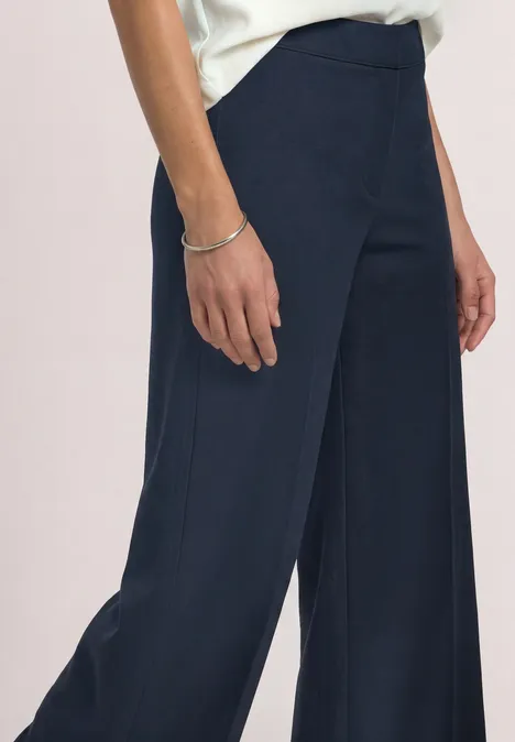 High Waist Straight Leg Hose im Casual Fit shadowed navy Damenkörper ab Taille in dunkelblauer, weiter Hose mit silbernem Armband am Handgelenk.