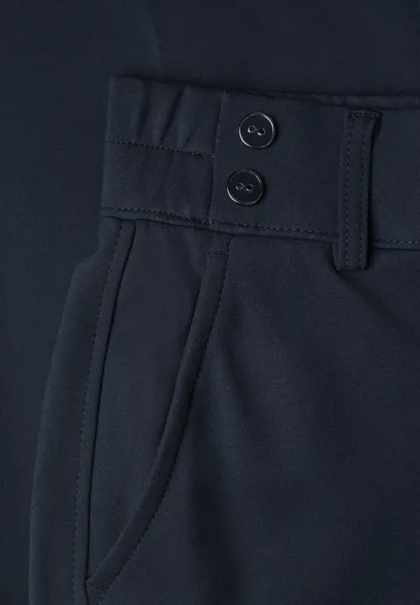 Nahaufnahme einer dunkelblauen Hose mit zwei Knöpfen, Gürtelschlaufen und seitlicher Tasche.