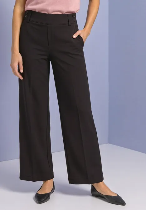 Schwarze, weite, gerade geschnittene Hose, kombiniert mit spitzen schwarzen Pumps und rosa Oberteil.