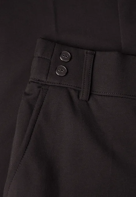 Nahaufnahme einer schwarzen Hose mit Gürtelschlaufen, zwei Bundknöpfen und seitlicher Tasche