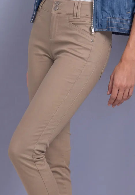 Une personne porte un pantalon beige moulant et une veste en jean bleue.