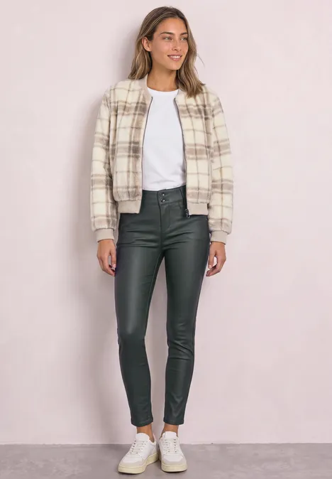 Femme en veste-chemise à carreaux, t-shirt blanc, leggings en cuir noirs et baskets blanches.