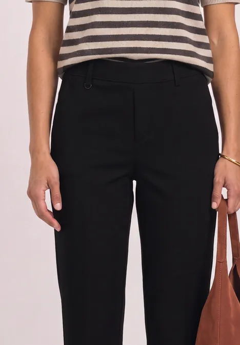 Haut rayé et pantalon noir taille haute, personne tient un sac marron.