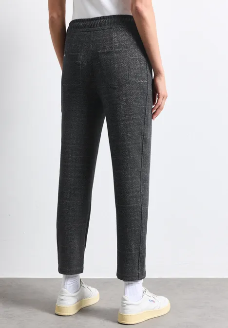 Vue arrière d’un pantalon gris à carreaux, coupe légèrement raccourcie, porté avec baskets blanches et chaussettes.