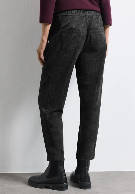 Pantalon noir fuselé avec poches arrière, porté avec des bottines noires.