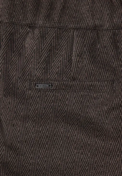 Close-up van donkerbruin visgraatstof met klein zakje en metalen plaatje