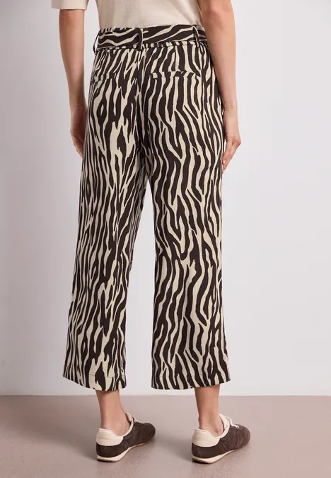 Vue arrière d'une personne portant un pantalon large à motif zèbre et des mocassins marron.