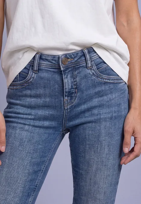 Blaue Denim-Jeans mit sichtbarem Bund und Taschen, kombiniert mit einem weißen Shirt.