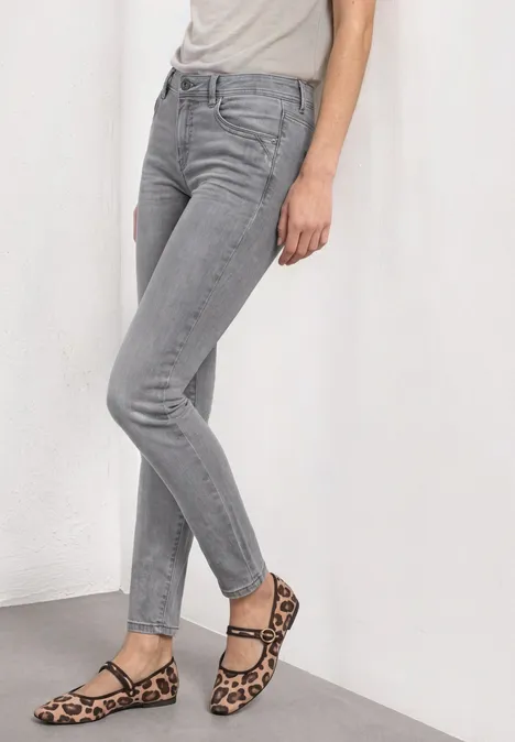 Mid Waist Slim Leg Jeans im Casual Fit Light Grey Random Washed Graue Skinny-Jeans und leo-gemusterte Riemchensandalen.