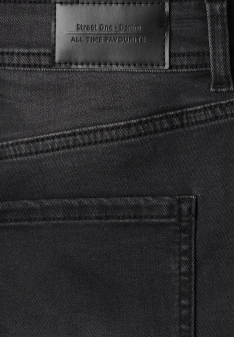 Zwarte jeans met label 'STUDIO CLM EDITION ALL THE FAVOURS' boven de achterzak.