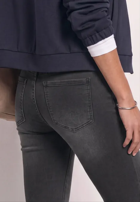 Persoon van achteren in donkergrijze skinny jeans en een donkerblauw bovenstuk.