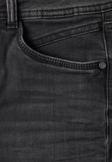 Close-up van een zwarte spijkerbroek met zichtbare zak en stiksel.