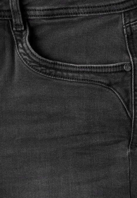 Close-up van een zwarte spijkerbroek met zichtbare zak en stiksels.