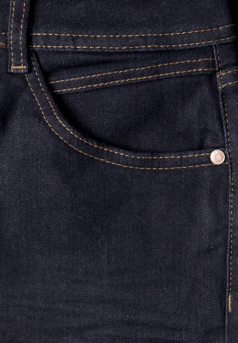 Close-up van een donkerblauwe spijkerbroek met zijzak, contrasterende stiksels en metalen klinknagel.