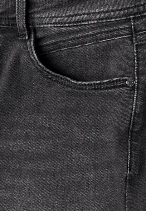 Gros plan d'un jean noir montrant la poche avant et les coutures