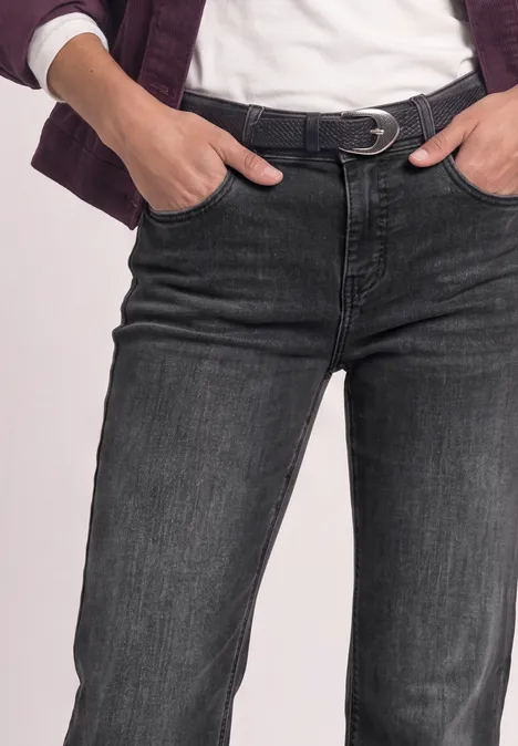 Personne porte un jean noir avec ceinture, mains dans les poches, t-shirt blanc et veste.
