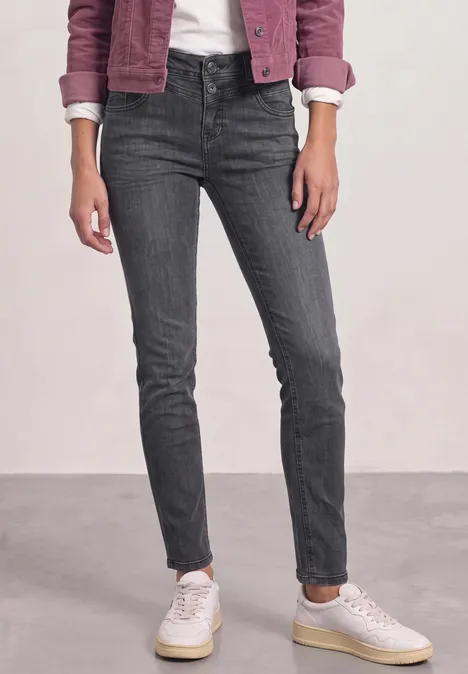Mid Waist Slim Leg Jeans im Casual Fit Steel Grey Wash Eine Person trägt dunkelgraue, eng anliegende Jeans und weiße Sneaker.