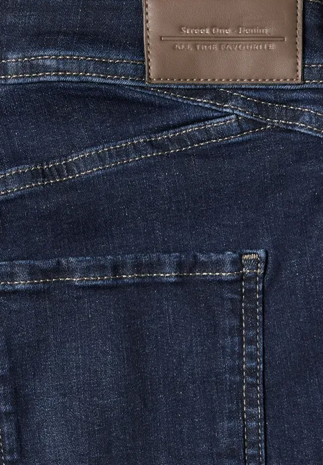 Nahaufnahme einer dunkelblauen Jeanshose mit Ziernähten und braunem Lederlabel am Bund