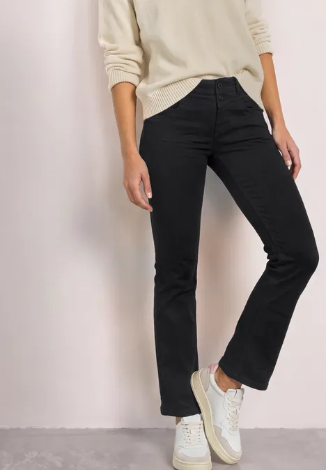 Personne en jean noir et baskets blanches, haut de couleur claire.