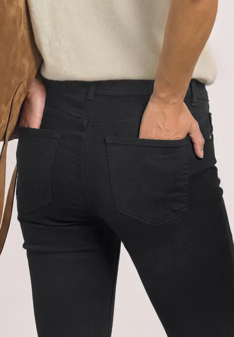 Personne vue de dos portant un jean noir, mains dans les poches arrière.
